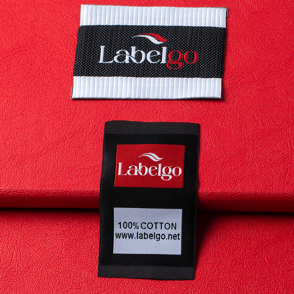 Zoom sur une étiquette tissée noire avec logo blanc et rouge LabelGo sur fond rouge.